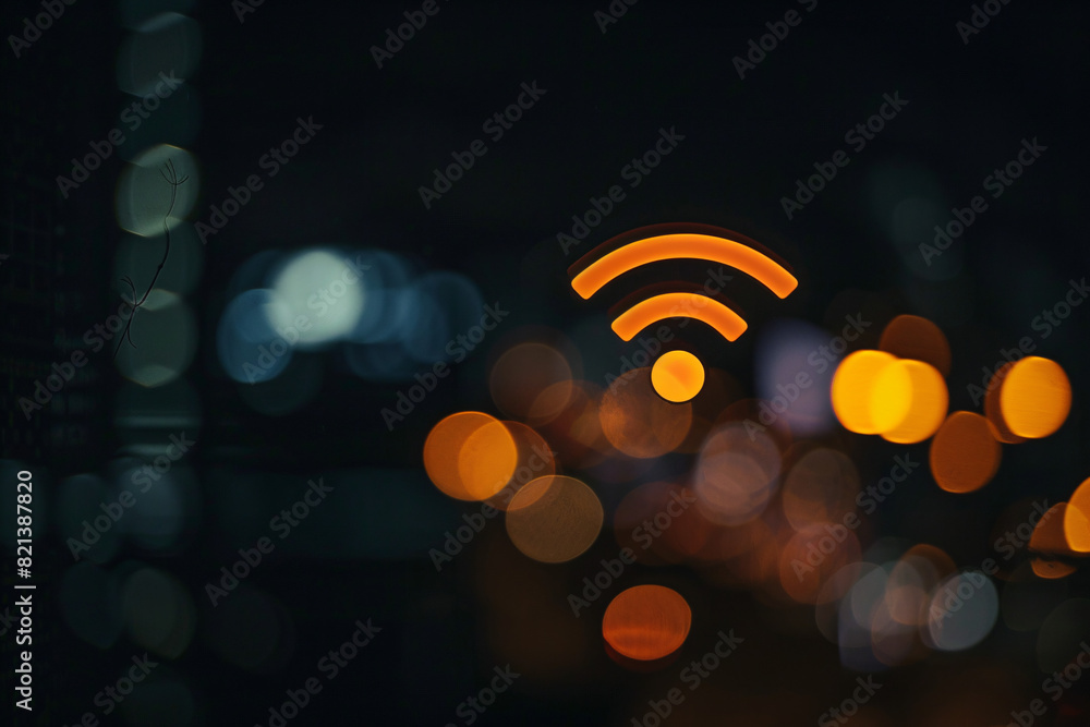 Obraz premium Orange Wi-Fi symbol over a blurred background with bokeh lights, representing connectivity in an urban setting