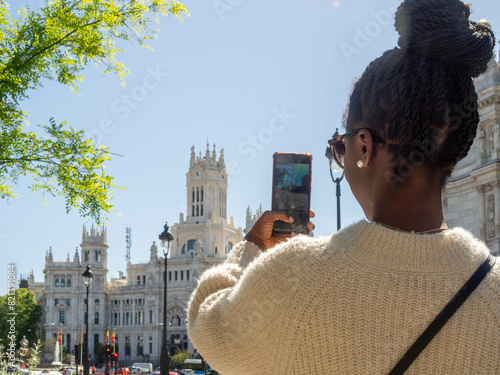 young woman sightseeing and taking a photo of a historic building in Madrid Spain