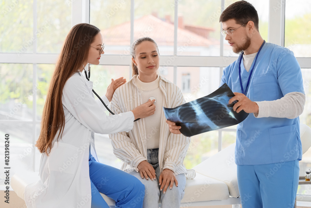 Fototapeta premium Doctors showing x-ray image of lungs to patient in clinic