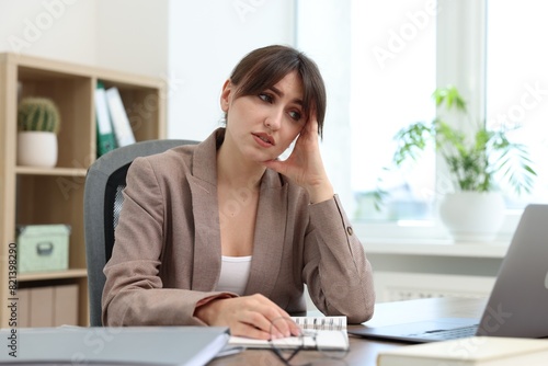 Overwhelmed office worker sitting at table with laptop indoors