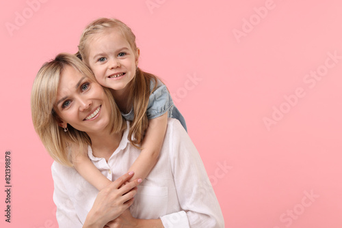 Daughter hugging her happy mother on pink background. Space for text