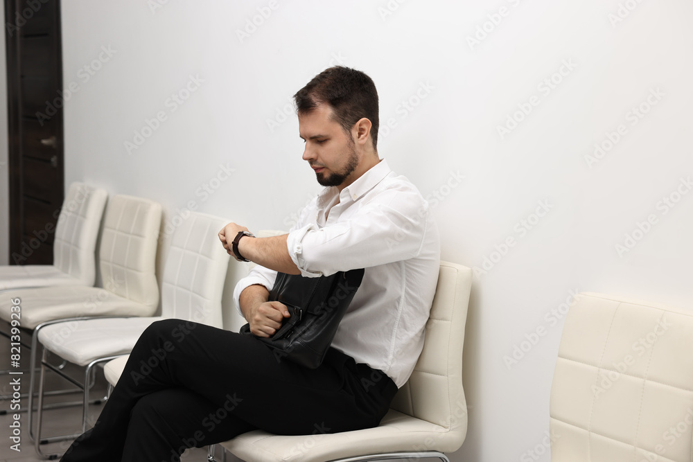Man looking at wrist watch and waiting for job interview indoors Man looking at wrist watch and waiting for job interview indoors