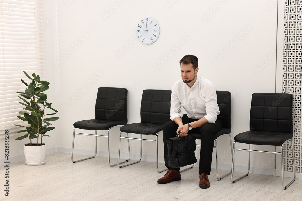 Man sitting on chair and waiting for job interview indoors Man sitting on chair and waiting for job interview indoors