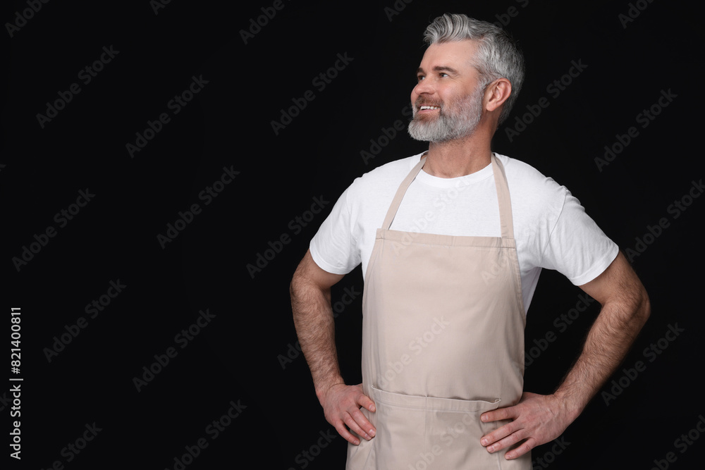 Happy man wearing kitchen apron on black background. Mockup for design Happy man wearing kitchen apron on black background. Mockup for design