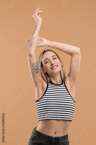 Portrait of beautiful tattooed woman on beige background © New Africa