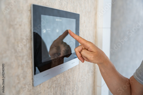 View of hand of man using tablet panel application for control smart home living. Wireless device controller for home automation IoT on the wall