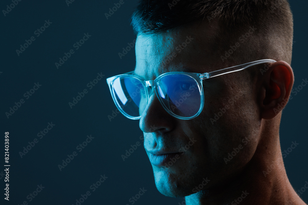 Obraz premium Portrait brutal man in glasses. Augmented reality game, future technology, AI concept. VR. Neon blue and red light. Dark background.