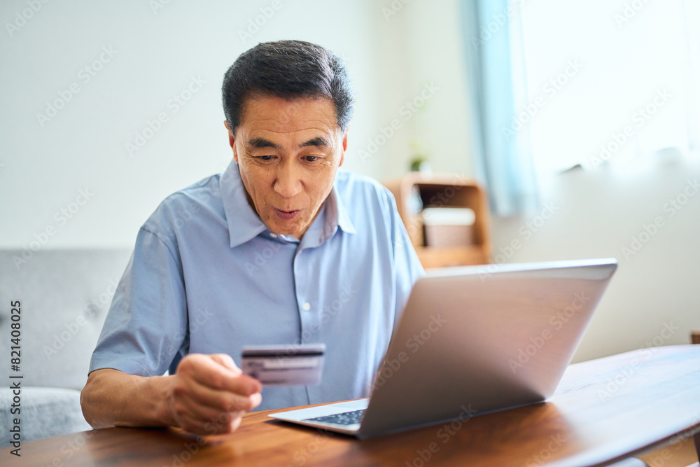 ネットショッピングでクレジットカード番号を打ち込むシニア男性