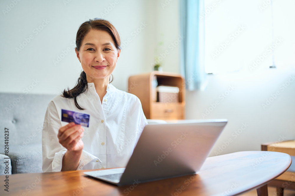 ネットショッピングでクレジットカード番号を打ち込むシニア女性 ネットショッピングでクレジットカード番号を打ち込むシニア女性