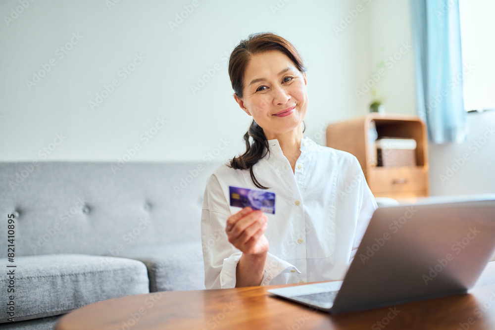 ネットショッピングでクレジットカード番号を打ち込むシニア女性 ネットショッピングでクレジットカード番号を打ち込むシニア女性