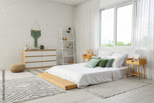 Comfortable bed and chest of drawers in interior of cozy bedroom