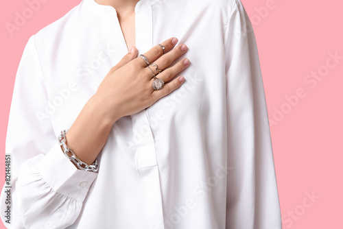 Beautiful young woman wearing stylish silver jewelry on pink background, closeup