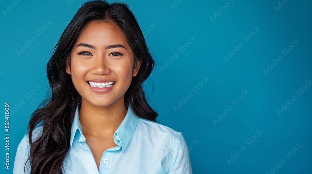 A modern stylish portrait of a professional woman smiling showing off her new braces on a blue background. A modern stylish portrait of a professional woman smiling showing off her new braces on a blue background.