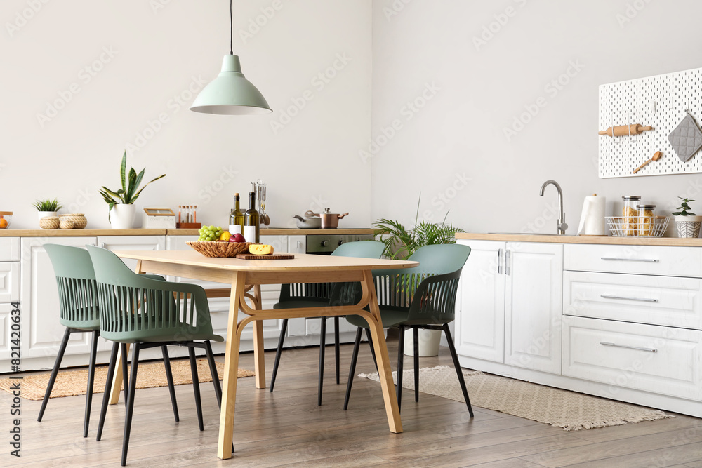 Interior of modern kitchen with dining table, chairs, white counters and lamp Interior of modern kitchen with dining table, chairs, white counters and lamp