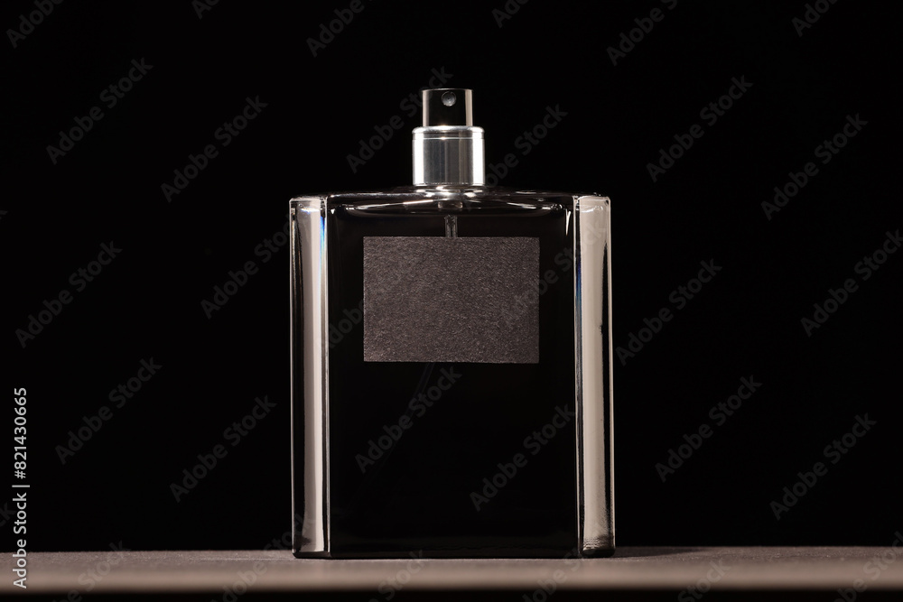 Luxury men`s perfume in bottle on grey table against black background Luxury men`s perfume in bottle on grey table against black background