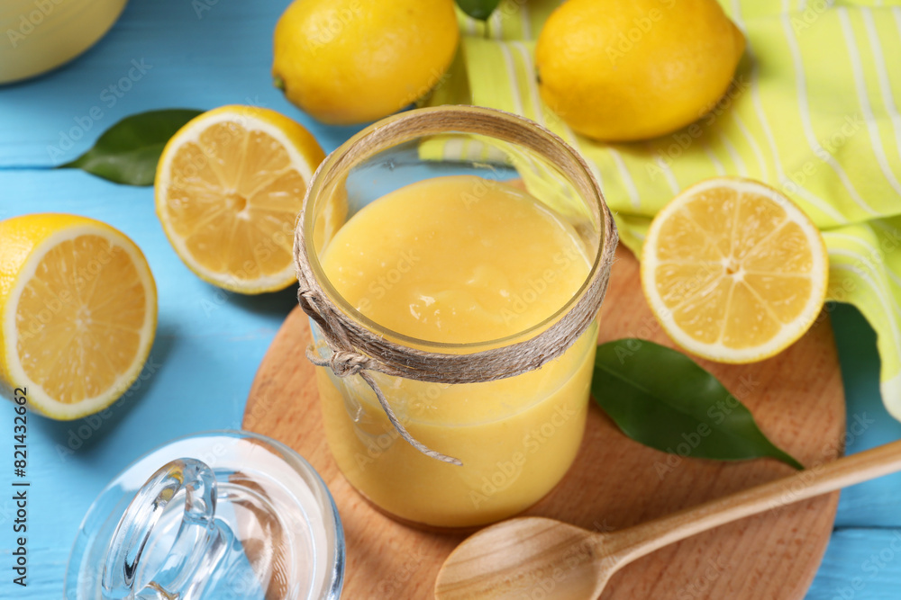 Delicious lemon curd in glass jar, fresh citrus fruits, green leaves and spoon on light blue wooden table Delicious lemon curd in glass jar, fresh citrus fruits, green leaves and spoon on light blue wooden table