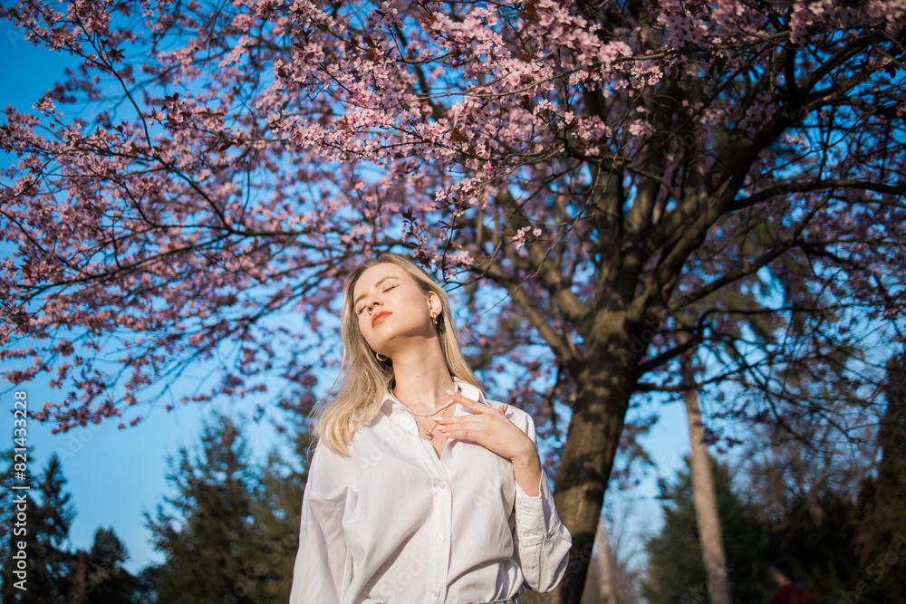 Woman with cherry flowers surrounded by blossoming trees copy space. Beauty and seasonal change and spring bloom season concept. Woman with cherry flowers surrounded by blossoming trees copy space. Beauty and seasonal change and spring bloom season concept.