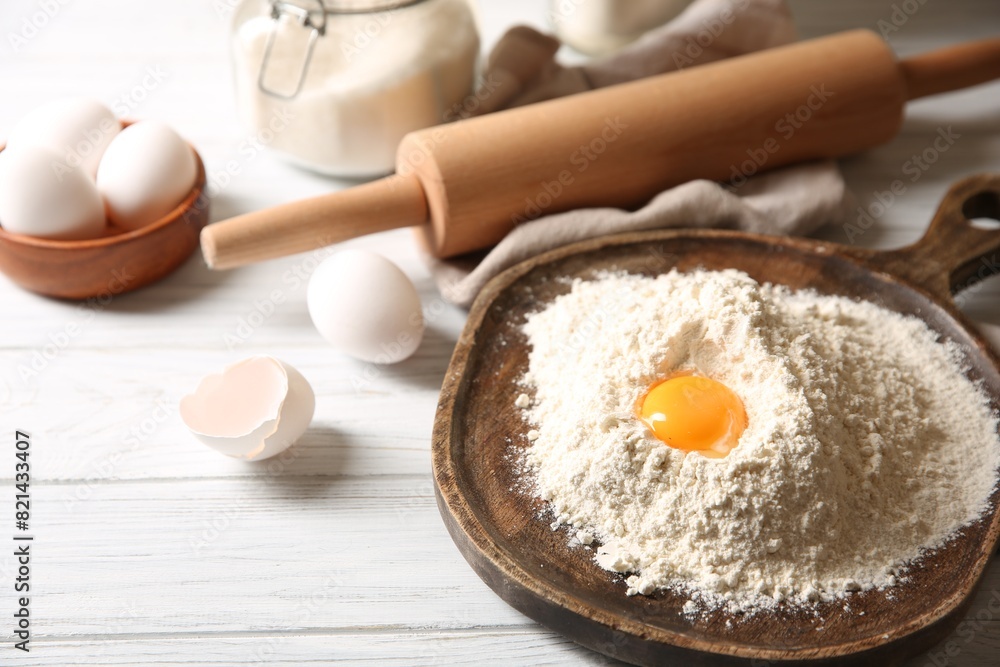 Making dough. Pile of flour with yolk, rolling pin and eggs on white wooden table, closeup Making dough. Pile of flour with yolk, rolling pin and eggs on white wooden table, closeup