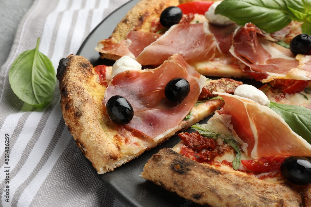 Tasty pizza with cured ham, olives, mozzarella cheese, sun-dried tomato and basil on table, closeup Tasty pizza with cured ham, olives, mozzarella cheese, sun-dried tomato and basil on table, closeup