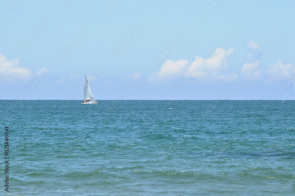 Obraz premium Small sailing boat with crew sailing in the middle of the ocean