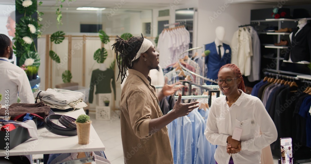 Obraz premium Content creator filming vlog intro, talking with SH clothing shop shopkeeper about helpful discounts to lure in clients. Internet star and retail clerk in discount store recording for social media