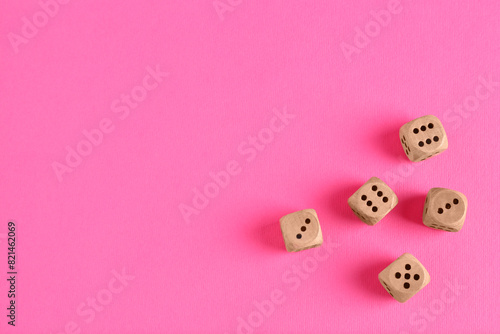 Many wooden game dices on pink background  flat lay. Space for text