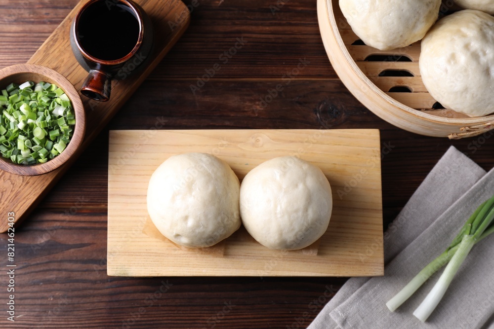 Delicious Chinese steamed buns, green onion and soy sauce on wooden table, flat lay Delicious Chinese steamed buns, green onion and soy sauce on wooden table, flat lay