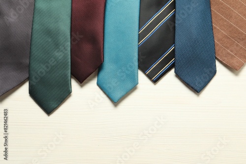 Different neckties on white wooden table, flat lay. Space for text