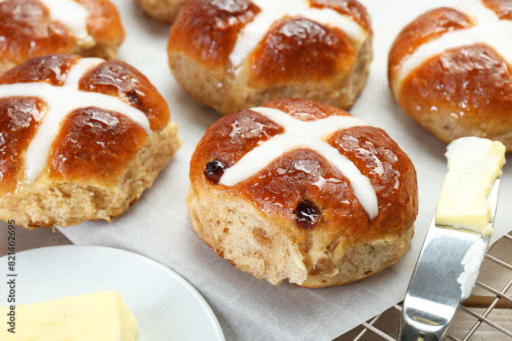 Tasty hot cross buns and knife with butter on table, closeup Tasty hot cross buns and knife with butter on table, closeup