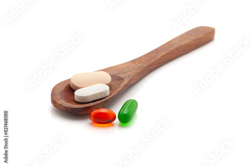 Health care concept. A wooden spoon filled with different Medical Tablets, Pills, and Capsules. Isolated on a white background.