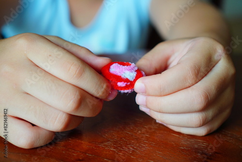 小学生の子供が赤いモールを束ねて丸めてる様子 photo