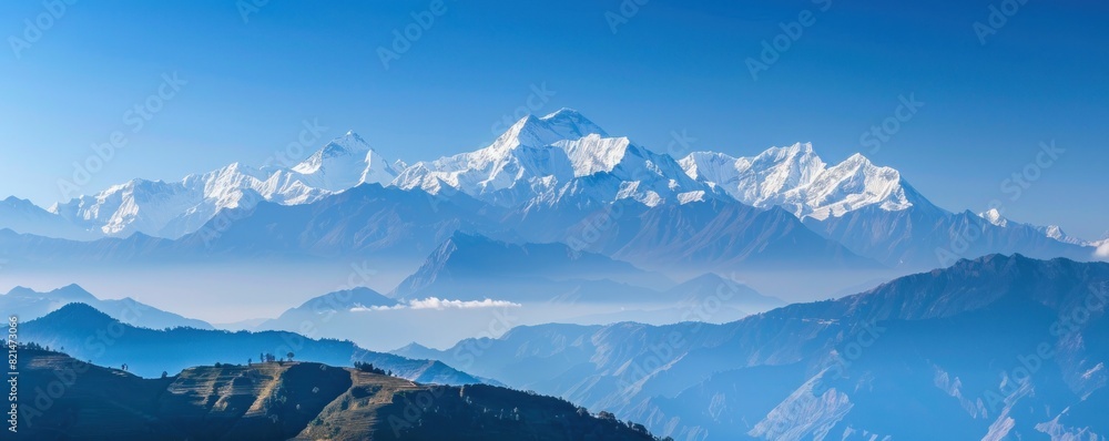 A beautiful mountain range with snow-covered peaks. The sky is clear and blue, and the mountains are spread out across the horizon. Concept of awe and wonder at the majesty of nature A beautiful mountain range with snow-covered peaks. The sky is clear and blue, and the mountains are spread out across the horizon. Concept of awe and wonder at the majesty of nature