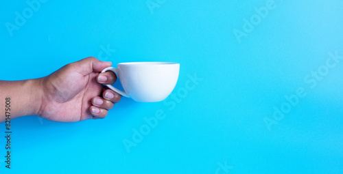 Hand people holding  white coffee cup peper filled with hot black coffee americano no sugar no milk ready to drink refreshing. aroma awake fresh to work placed on blue isolated background copy space. photo