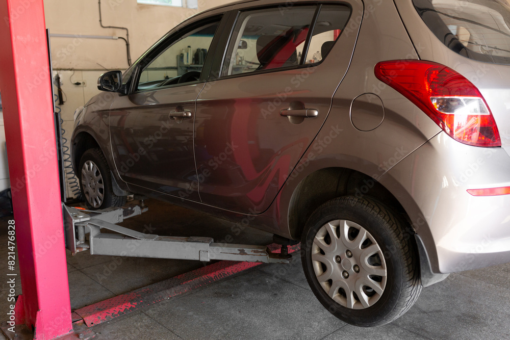 Car lift under a car for under the bottom of a car. The car is top notch. mechanical tools for car repair. car service center Car lift under a car for under the bottom of a car. The car is top notch. mechanical tools for car repair. car service center