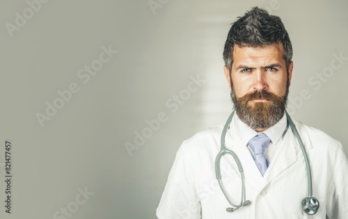 Healthcare, treatment and medical staff concept. Serious doctor in medical gown with stethoscope on neck. Handsome male intern, physician in white coat in clinic, hospital. Copy space for advertising.