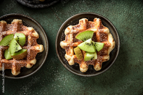 Morning waffles with kiwi and fork on a green surface photo