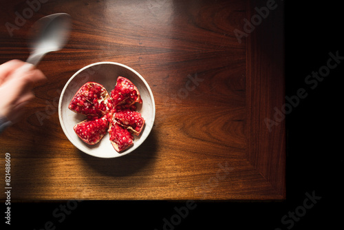 Pomegranate in ceramic bowl on wooden table. photo