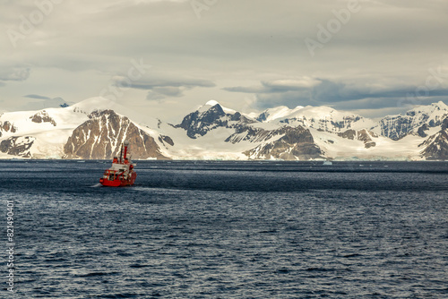 Red Research Scientific Vessel Alone on the Vast Ocean in Front of Snowclad Mountains Near Adelaide Island, Antarctica Peninsula