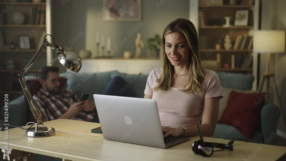 Beautiful Female Sitting at a Desk in a Cozy Living Room and Using Laptop Computer at Home Beautiful Female Sitting at a Desk in a Cozy Living Room and Using Laptop Computer at Home