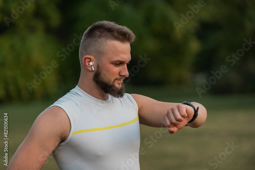 A happy runner man looking at a monitor watch checking heart rate while running or jogging in the park active healthy lifestyle.
