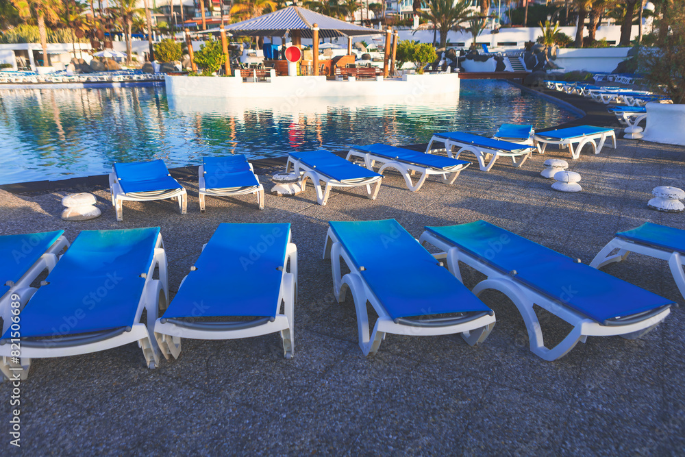 Lounge chairs by a pool, perfect for relaxing under the sun on vacation. Poolside lounge chairs