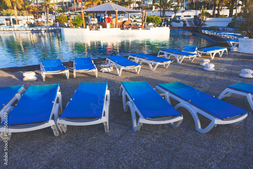 Lounge chairs by a pool, perfect for relaxing under the sun on vacation. Poolside lounge chairs