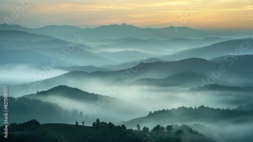 A misty mountain landscape at sunrise, with layers of hills visible through the fog. 