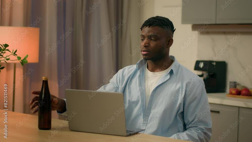 African American man at table kitchen drunk male addicted guy alcohol addiction drinking beer at home evening bad habit laptop looking at computer watching online game relax alcoholism health problem African American man at table kitchen drunk male addicted guy alcohol addiction drinking beer at home evening bad habit laptop looking at computer watching online game relax alcoholism health problem