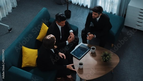 Top view of diverse people present financial chart to caucasian investor while sitting at meeting room. Smart businessman listening business plan and marketing strategy from startup team. Directorate.