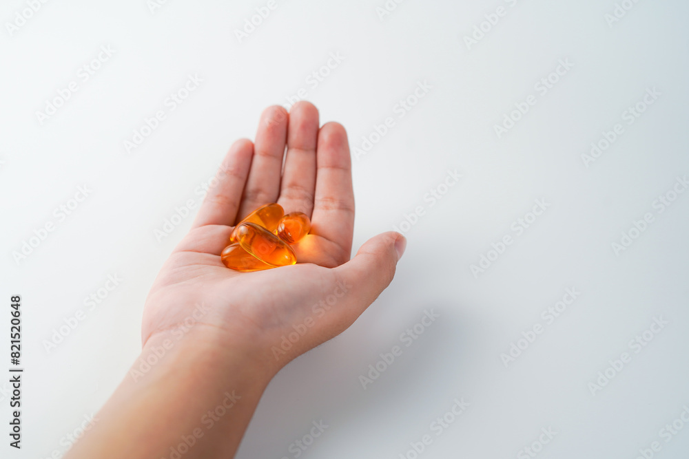 fingers holding a oil filled capsule, soft gel, food supplements, fish oil, omega 3 omega 9 fingers holding a oil filled capsule, soft gel, food supplements, fish oil, omega 3 omega 9