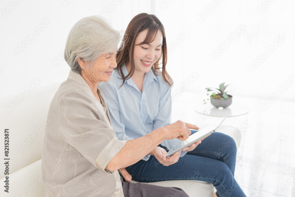 Obraz premium Asian female and mother search information with tablet computer, they feeling happy and smile, old people learning to use laptop, mother's day and happiness family time, technology and social network