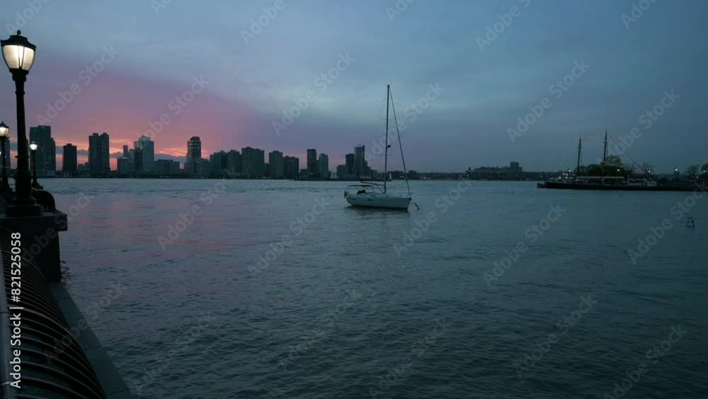 Experience the enchanting sunset over the Hudson River near Hudson Yards in this stunning video. Watch as the sky transforms into a canvas of pink and blue hues, with the city's lights beginning to tw