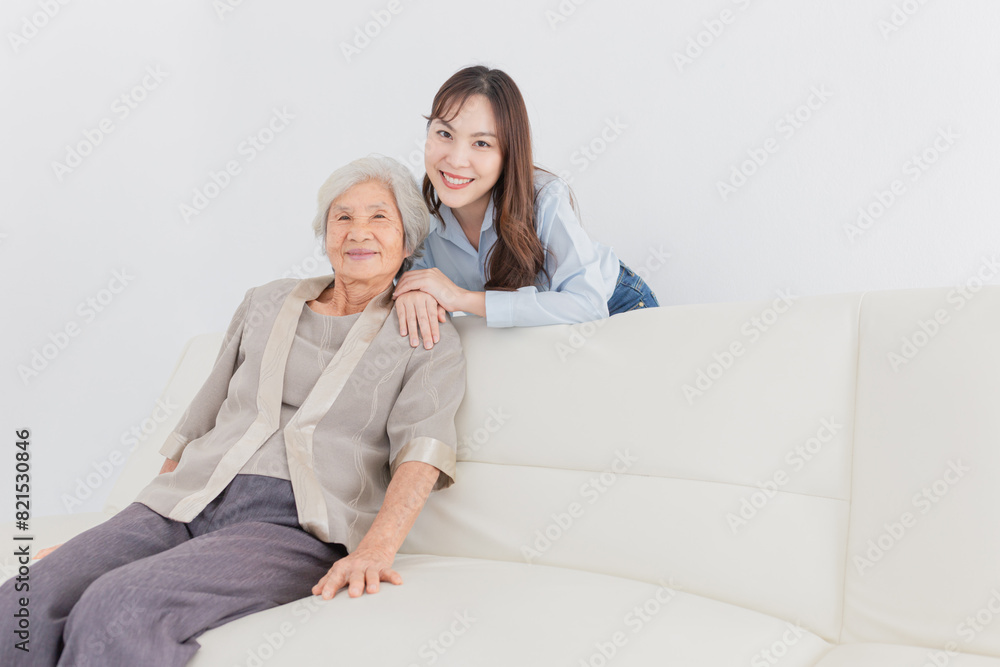 old Asian female sitting on sofa, young asian female rest hand on sofa, they feeling happy and smile in relax time, mother's day, happiness elderly in family time old Asian female sitting on sofa, young asian female rest hand on sofa, they feeling happy and smile in relax time, mother's day, happiness elderly in family time