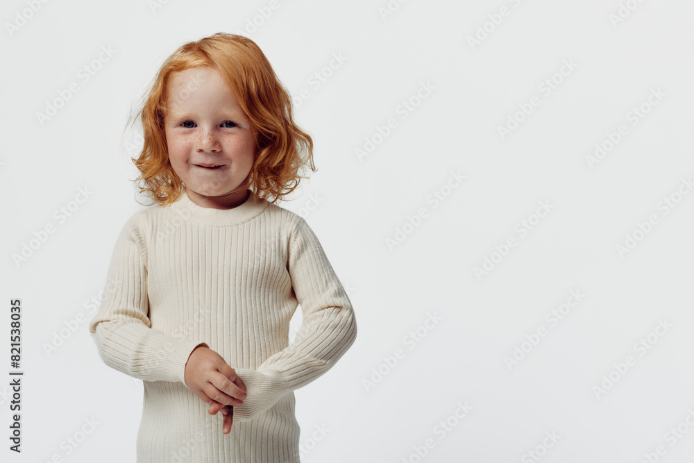 Red haired girl in white sweater standing in front of white background in a fashionable pose Red haired girl in white sweater standing in front of white background in a fashionable pose